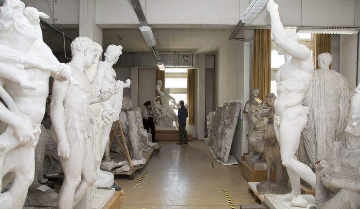 Zwei Studierende stehen in der Sammlung und betrachten die Gipsabgüsse.